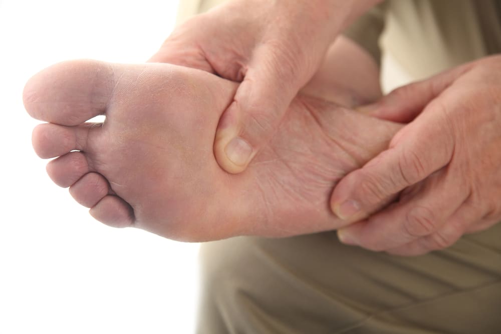 image of adult hands applying pressure to the sole of a foot
